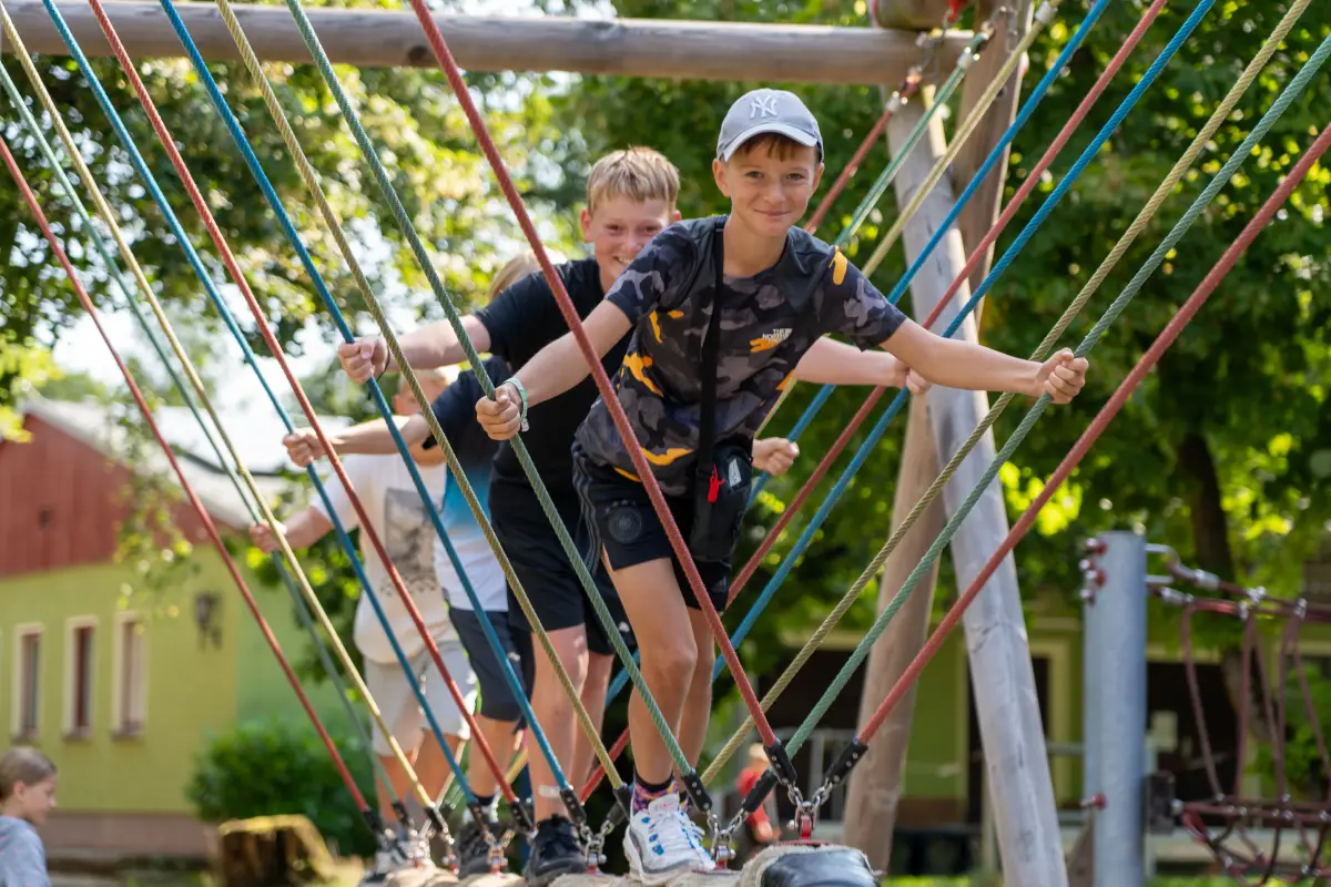 Boys balancing on a low rope course among the trees