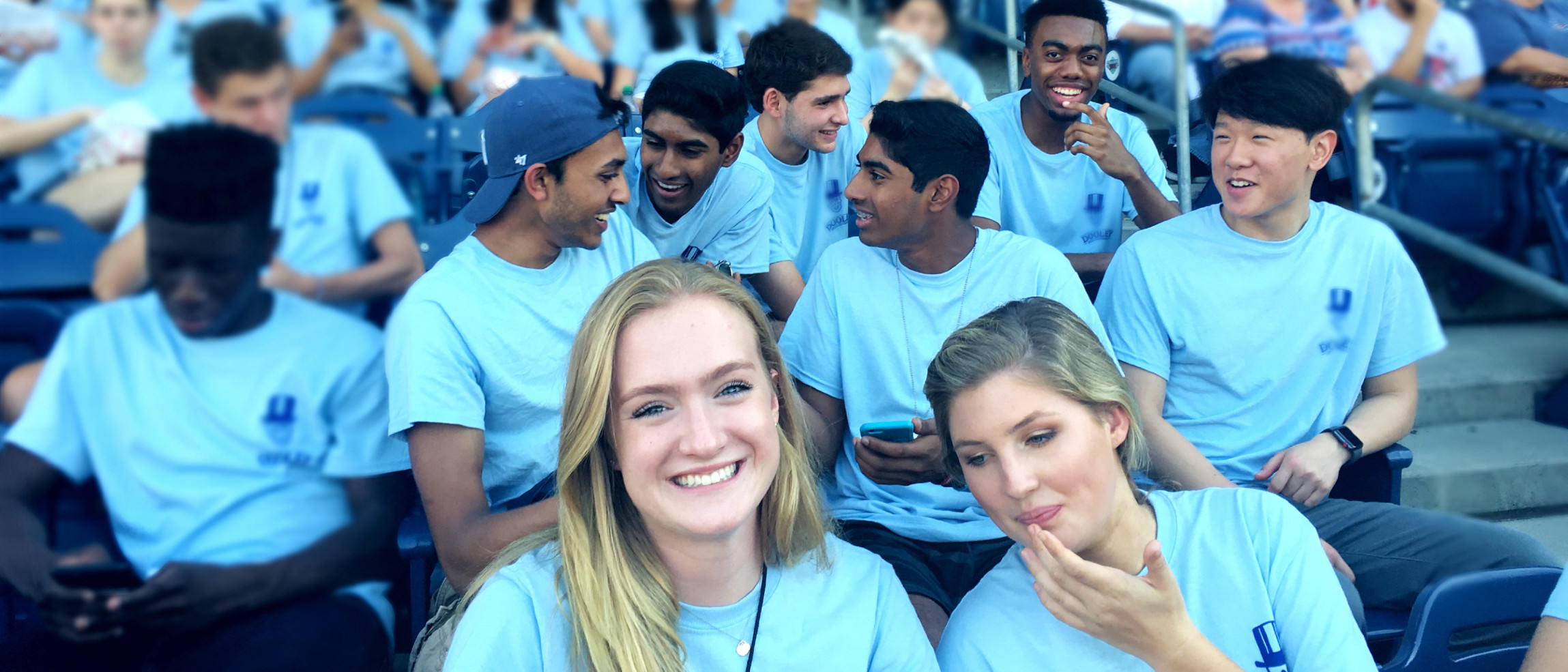Emory Pre-College students in matching light-blue programme T-shirts in the stands at an Atlanta sports outing