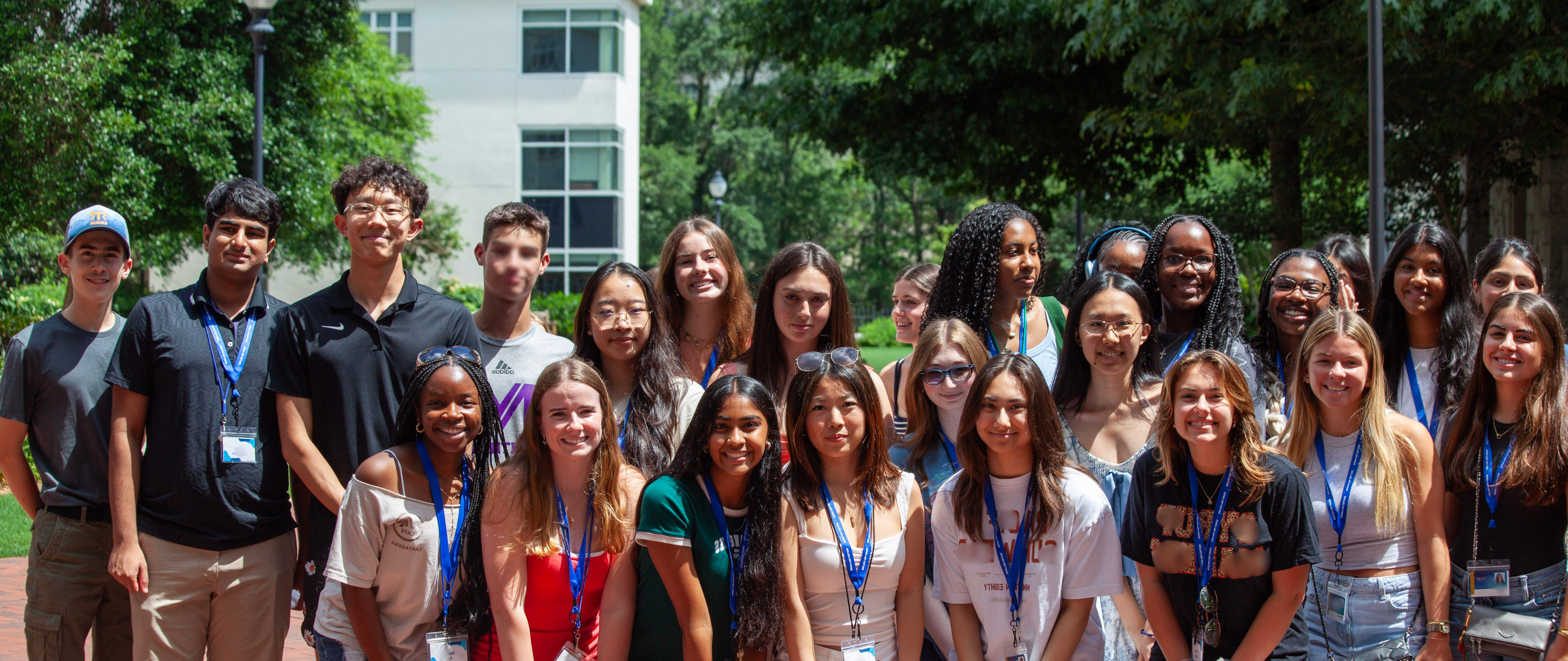 A full session group of Emory Pre-College students with programme lanyards, photographed outdoors beside Turman Hall