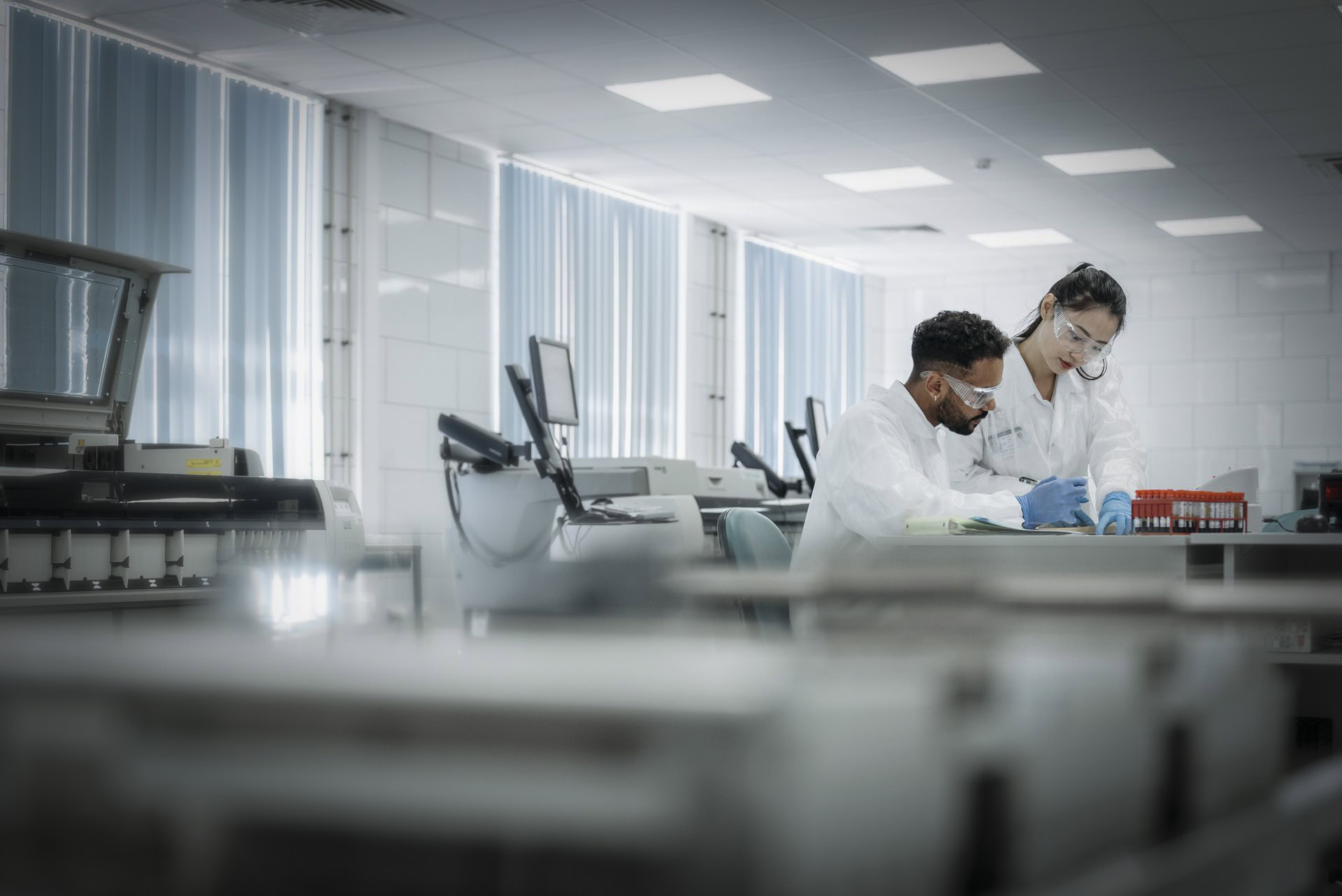 Two people in white lab coats work at a bench in a modern laboratory