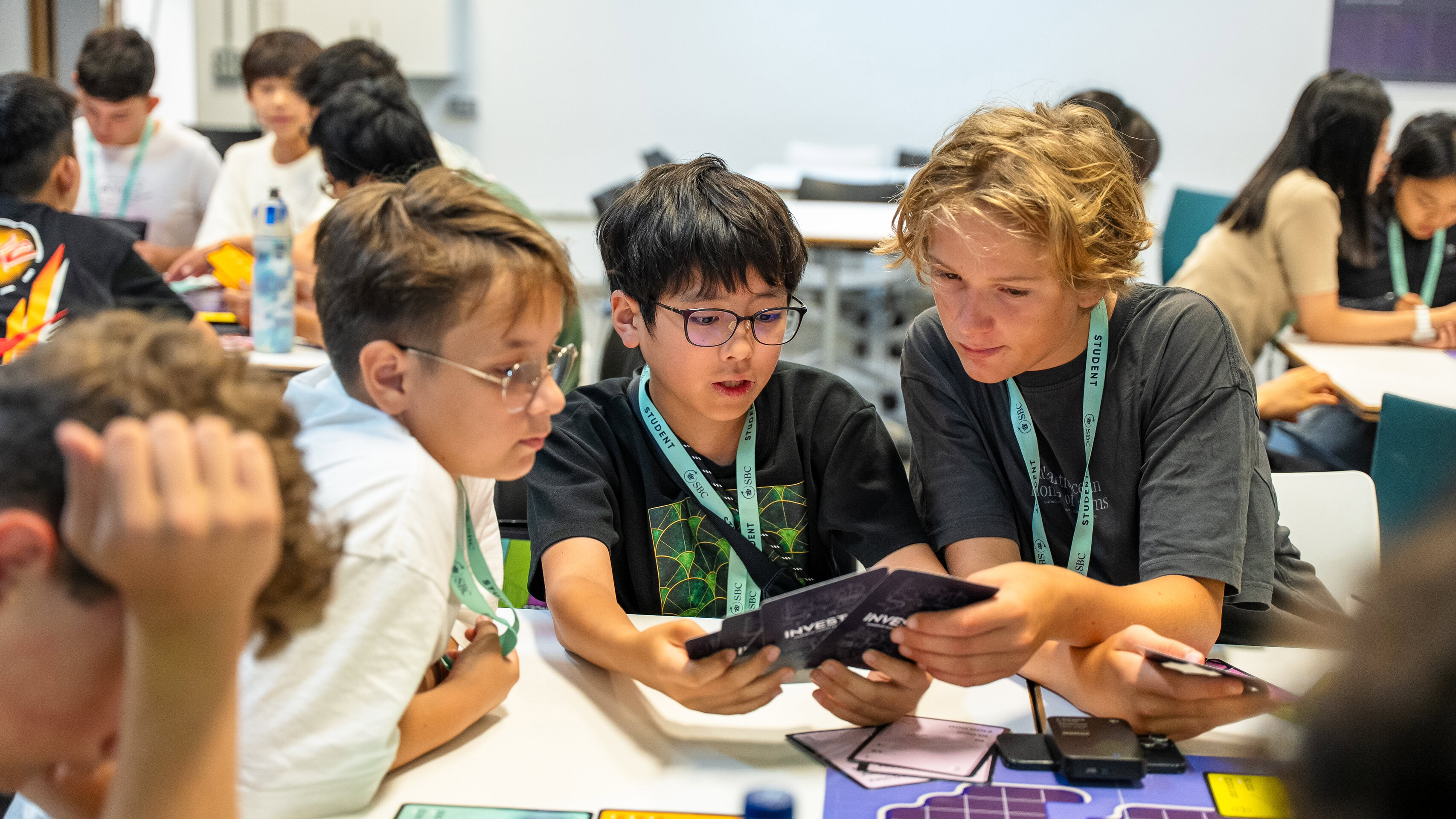 Three students look at a small screen together during a workshop at a table