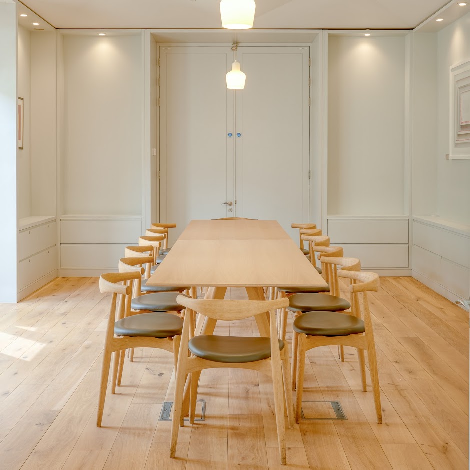 A long wooden table and chairs in an empty white seminar room
