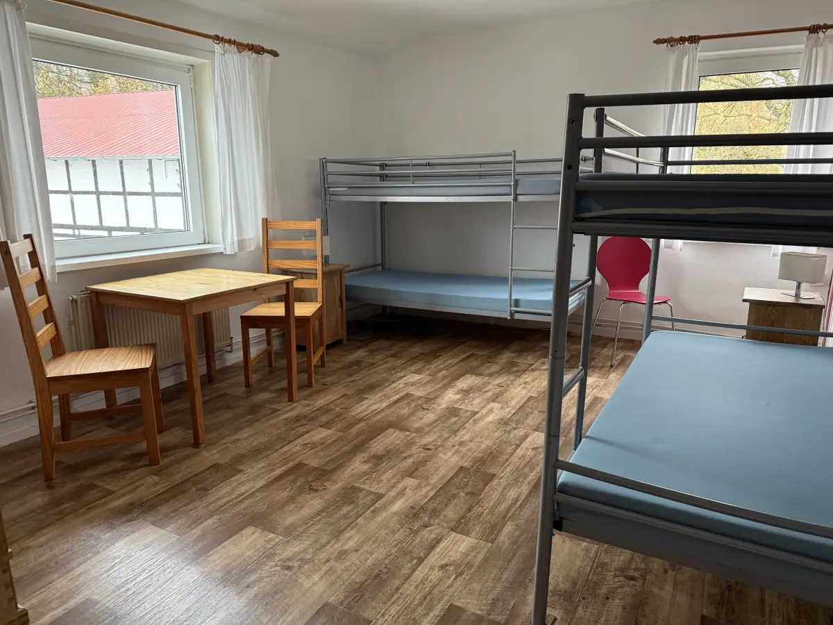 A multi-bed room at Haflingerhof Kattien with a bunk bed, a single bed, a wooden table and chairs