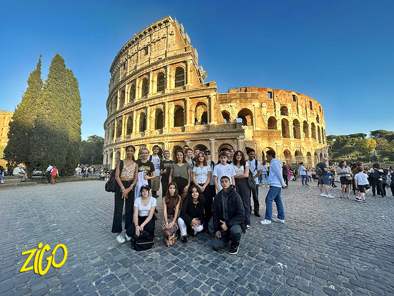 Group of teenagers posing in front of the Colosseum in Rome on a sunny day