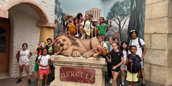 Campers beside the Hercule lion statue at the theme park