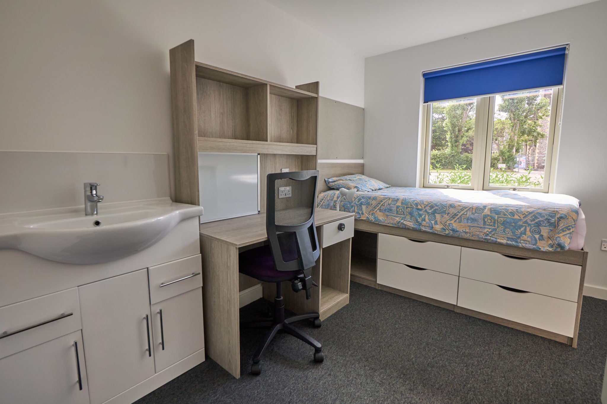 Single student bedroom with bed, desk and washbasin in a Hurst College boarding house
