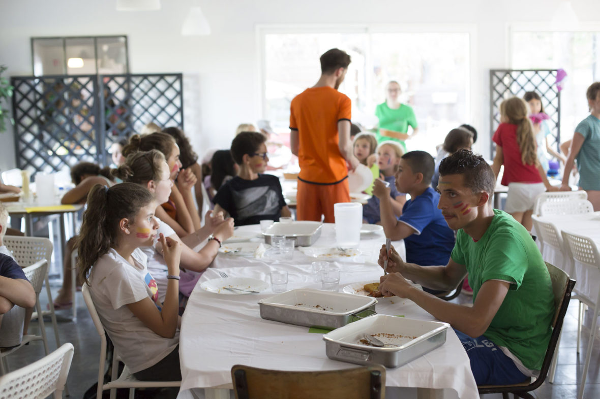 Campers eating together at long tables in the dining room