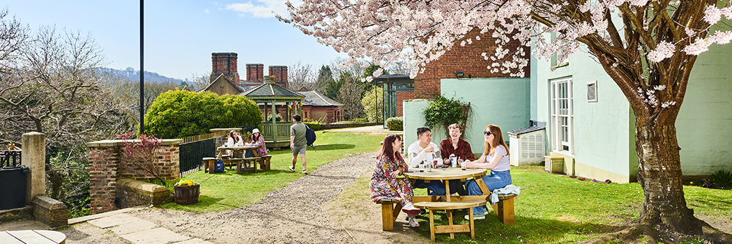 Students at outdoor wooden tables under blossom trees at Durham University