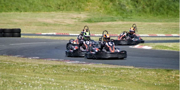 Pack of karts racing side by side through a bend of the circuit