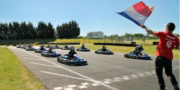Go-karts lined up on the start-finish straight as the flag is waved