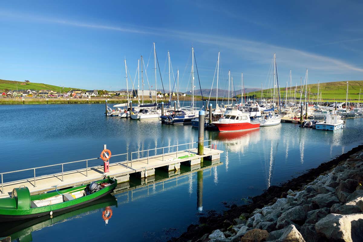 Coastal road above a rocky inlet with boats moored on the water at sunset
