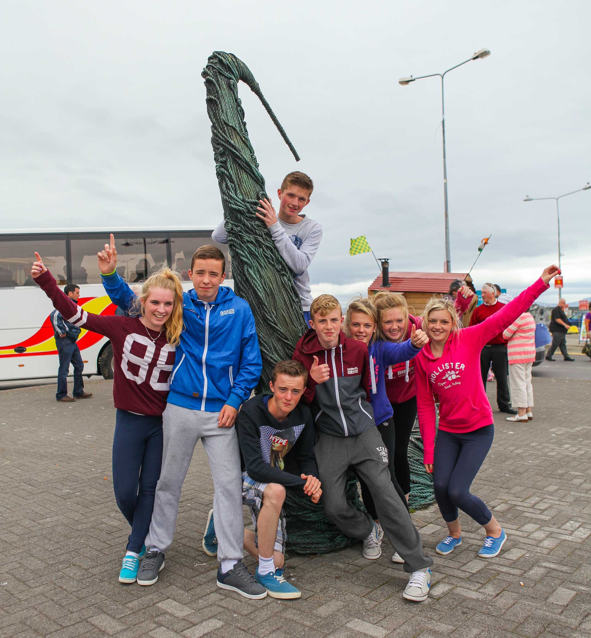 Group of students in college jackets gathered on the quayside at Dingle harbour