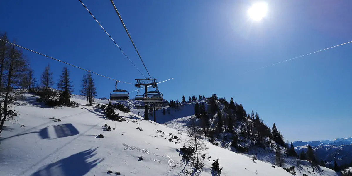 Chairlift running up a snow-covered slope under a clear sky