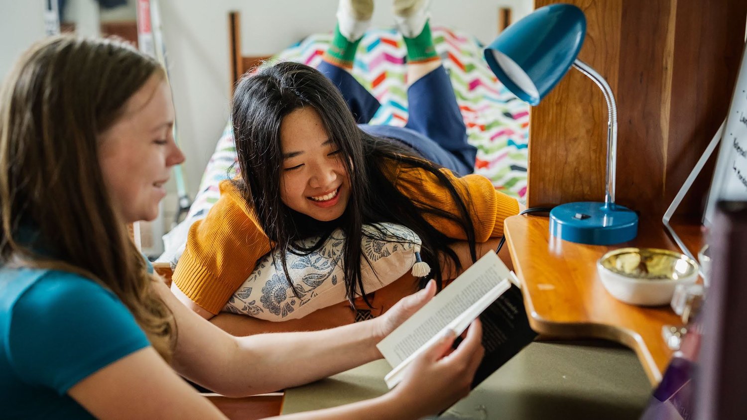 Two students reading and talking together in a campus residence room