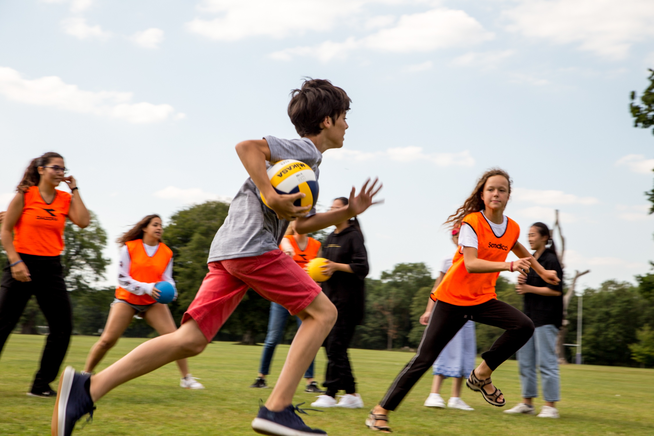Students playing a ball game on the grass in the school grounds