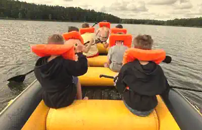 Children in life jackets paddling an inflatable boat on the Braunsteich lake