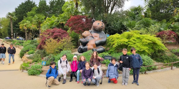 Campers gathered by the big bear sculpture in the zoo's landscaped gardens