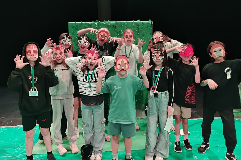 Students in costume performing on stage at the end of the course
