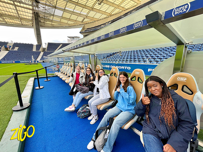 Group of young people sitting in the blue seats of the Dragões football stadium in Porto