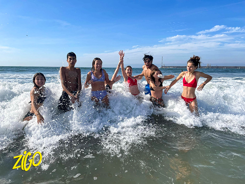 Group of young people standing in the breaking waves on a city beach