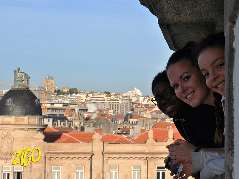 Participants leaning out from a terrace with the rooftops and domes of the city behind them