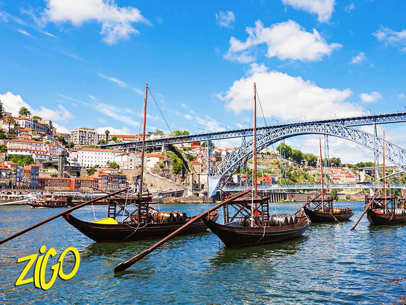 Traditional flat-bottomed rabelo boats on the Douro with the iron arch of the bridge behind