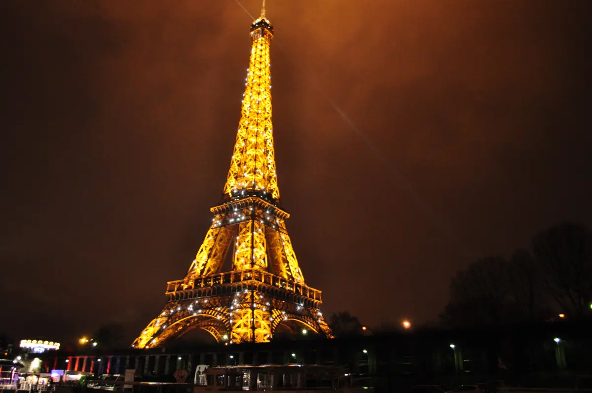 The Eiffel Tower in golden floodlight against a dark sky