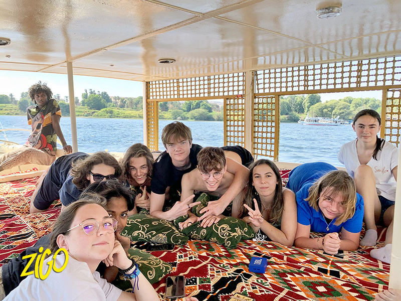 Participants lying together on the cushioned deck of the felucca as it sails down the Nile
