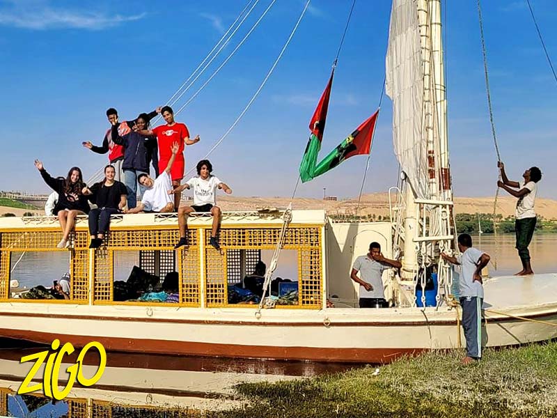 Participants sitting along the rail of the traditional sailing boat moored on the Nile