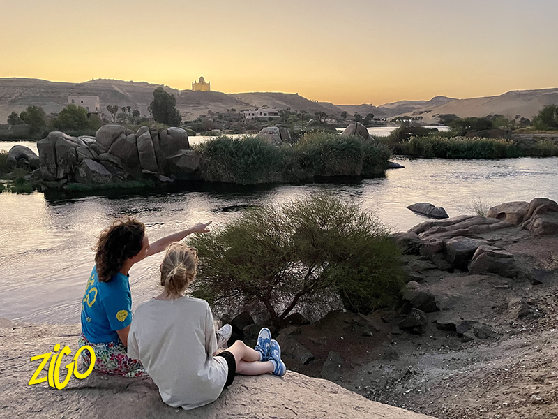 Two participants sitting on the bank of the Nile among the granite rocks near Aswan