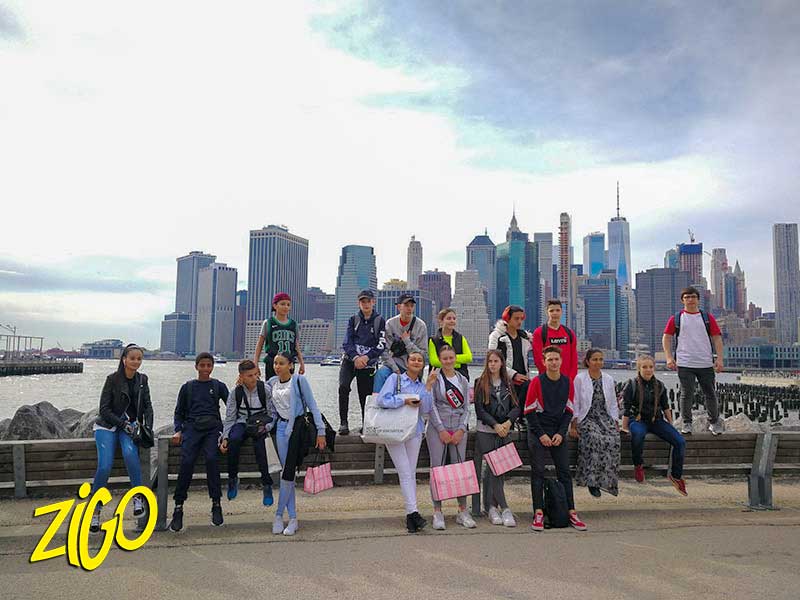 A group of young people on the Brooklyn waterfront with the Manhattan skyline behind them