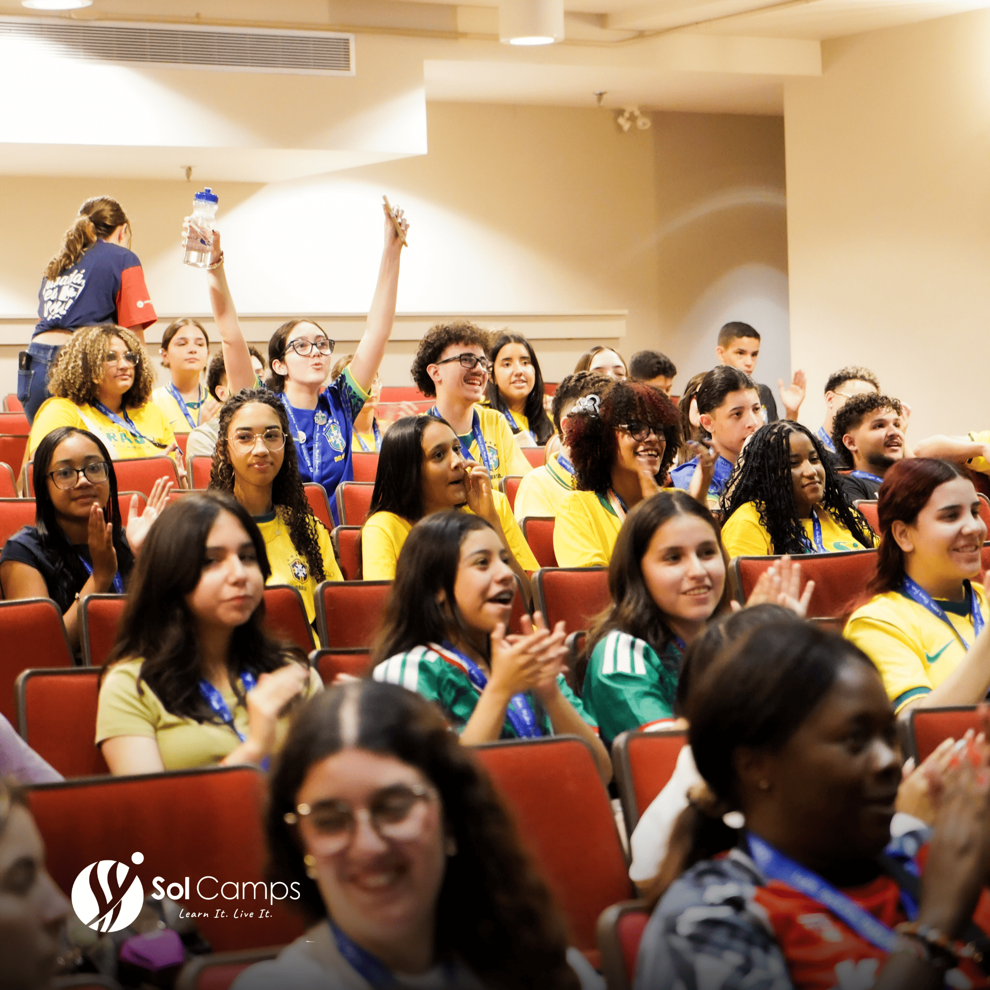 Sol Camps New York campers cheering in a lecture auditorium during a camp assembly