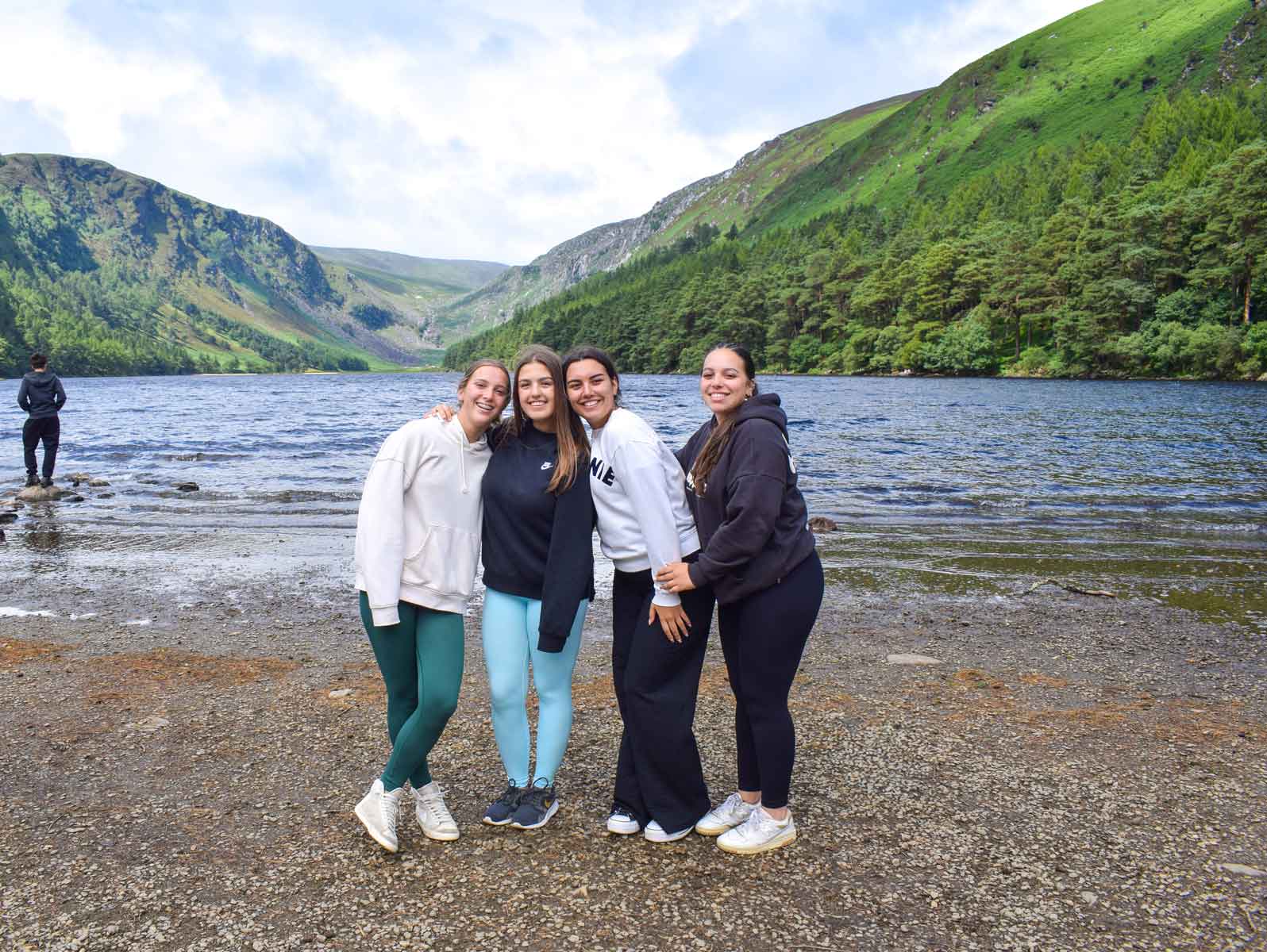 Camp students standing together on the shore of a lake in a green Irish valley during a full-day excursion