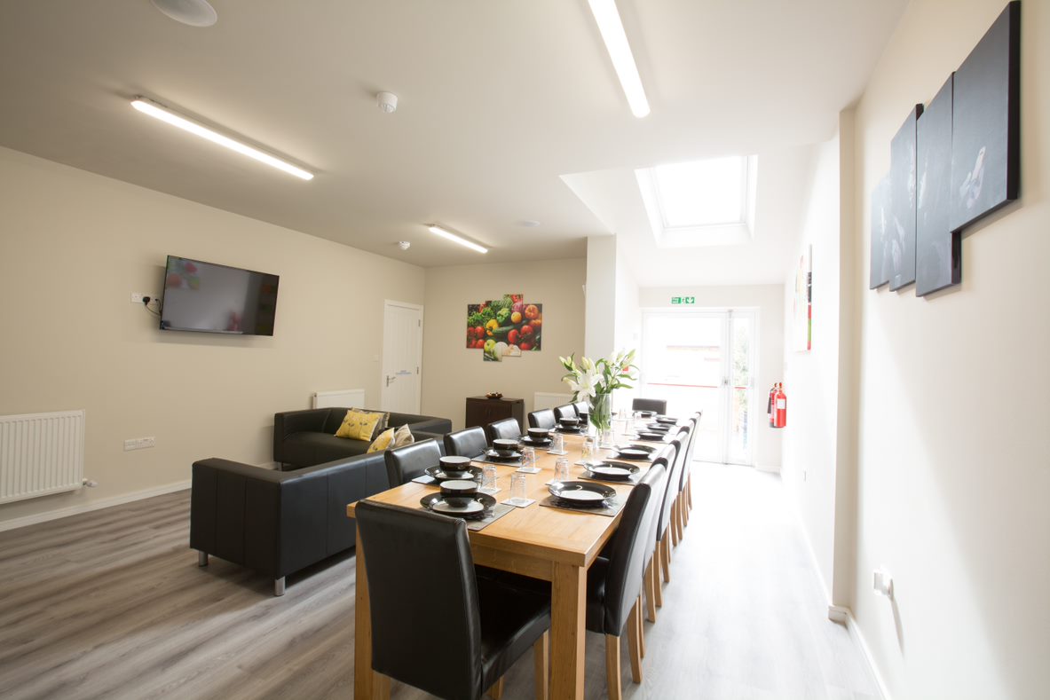 Common room in a Select English residence with a long dining table, sofa and television