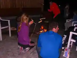 Children toasting sausages and marshmallows over a campfire in the evening at Villa Frida