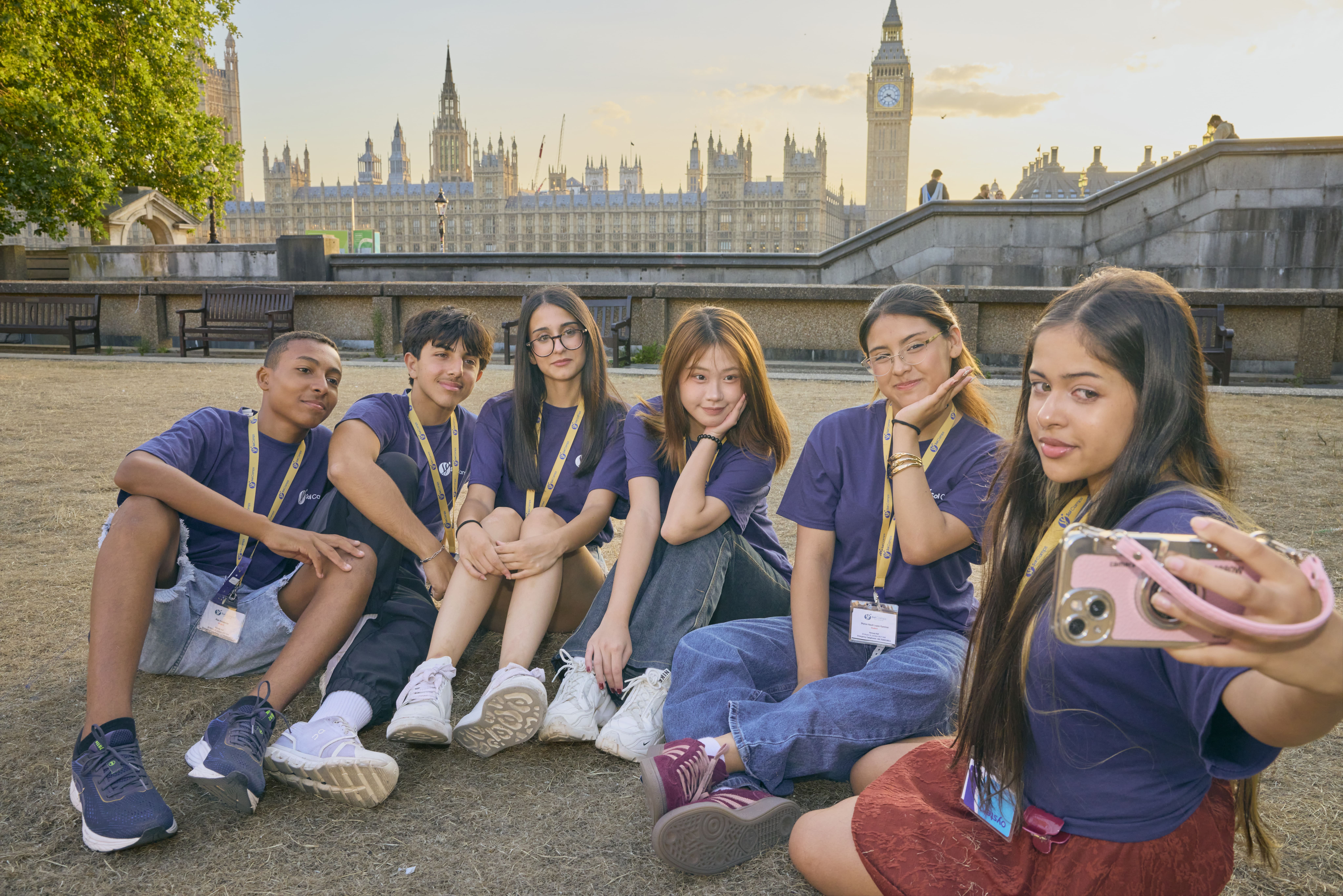 Sol Camps London teens in camp T-shirts and lanyards taking a selfie by the Thames with the Houses of Parliament behind them