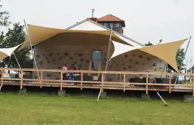 Bouldering wall and wooden terrace under sun sails at Sporthostel Schubybeach