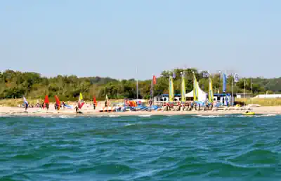 The surf school with boards and sails on the beach at Schubystrand seen from the Baltic Sea