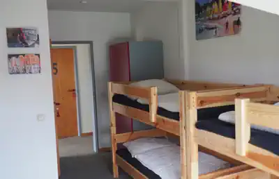 Multi-bed room with wooden bunk beds at Sporthostel Schubybeach