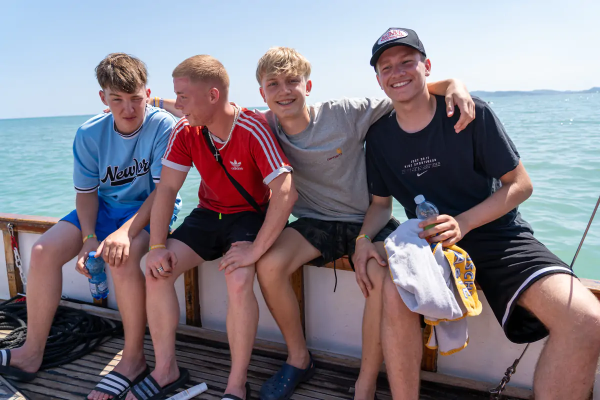 Four boys sitting side by side on a pedalo at the water’s edge on the Adriatic beach