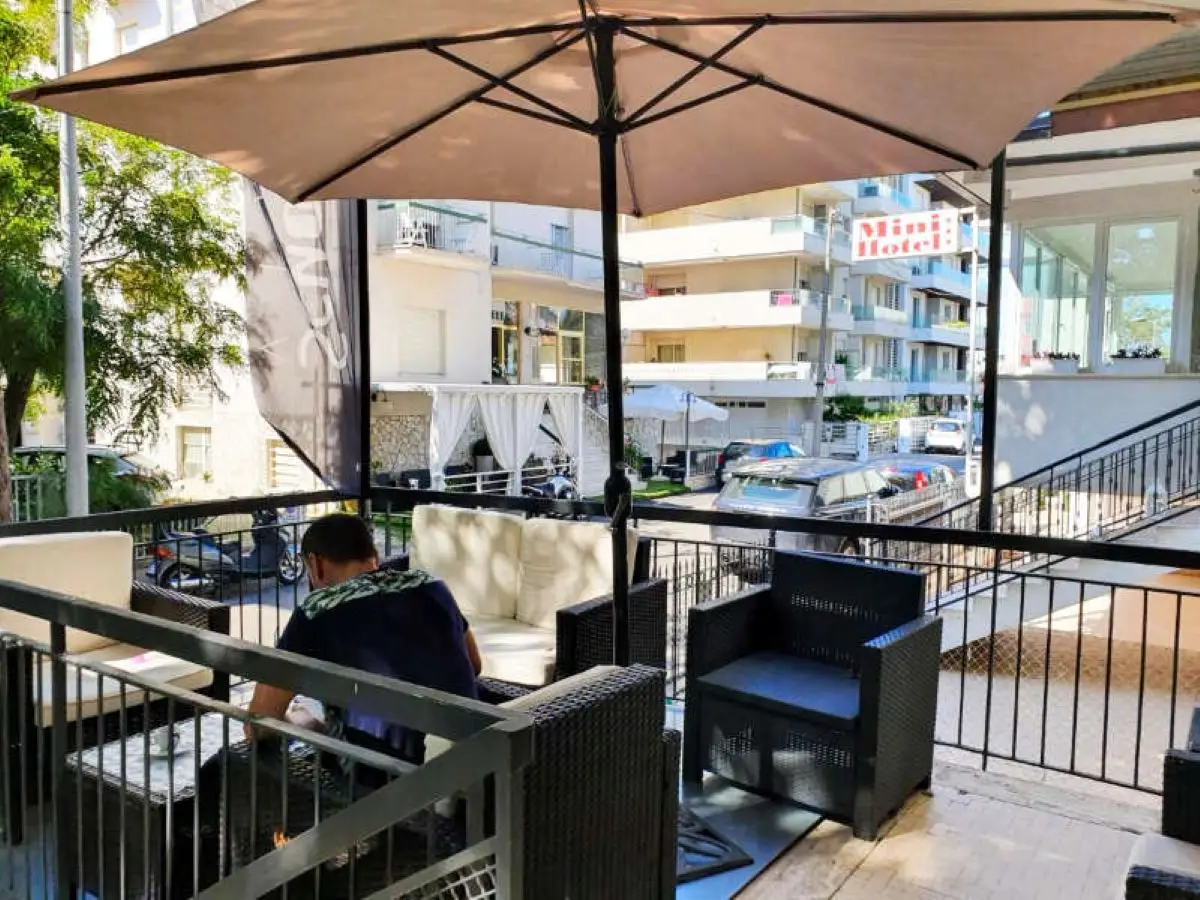 The shaded hotel terrace with a parasol and seating, looking out over the street