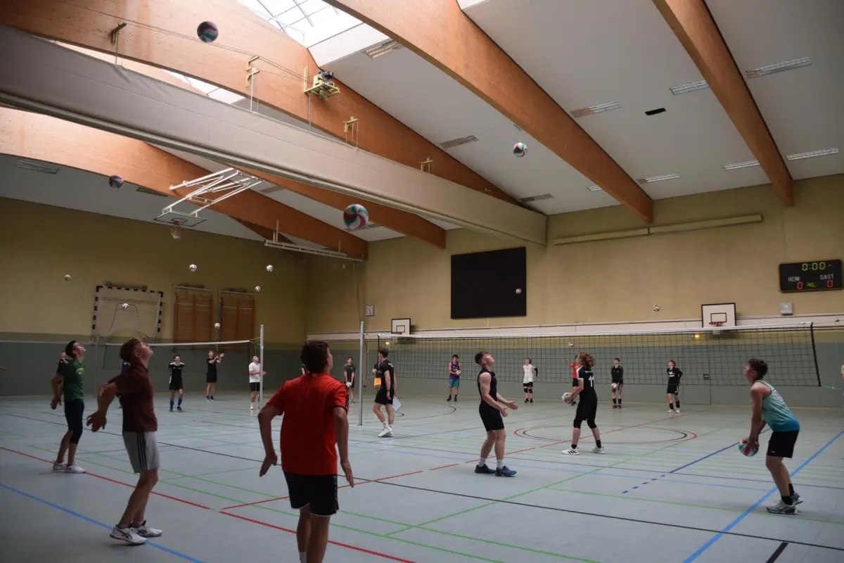 Large sports hall with volleyball nets and players training