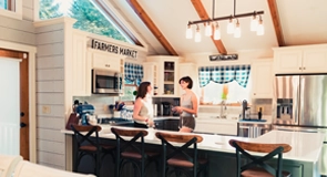 Open-plan kitchen of an LSI homestay in San Diego, with a breakfast bar and stools and two people at the counter behind.