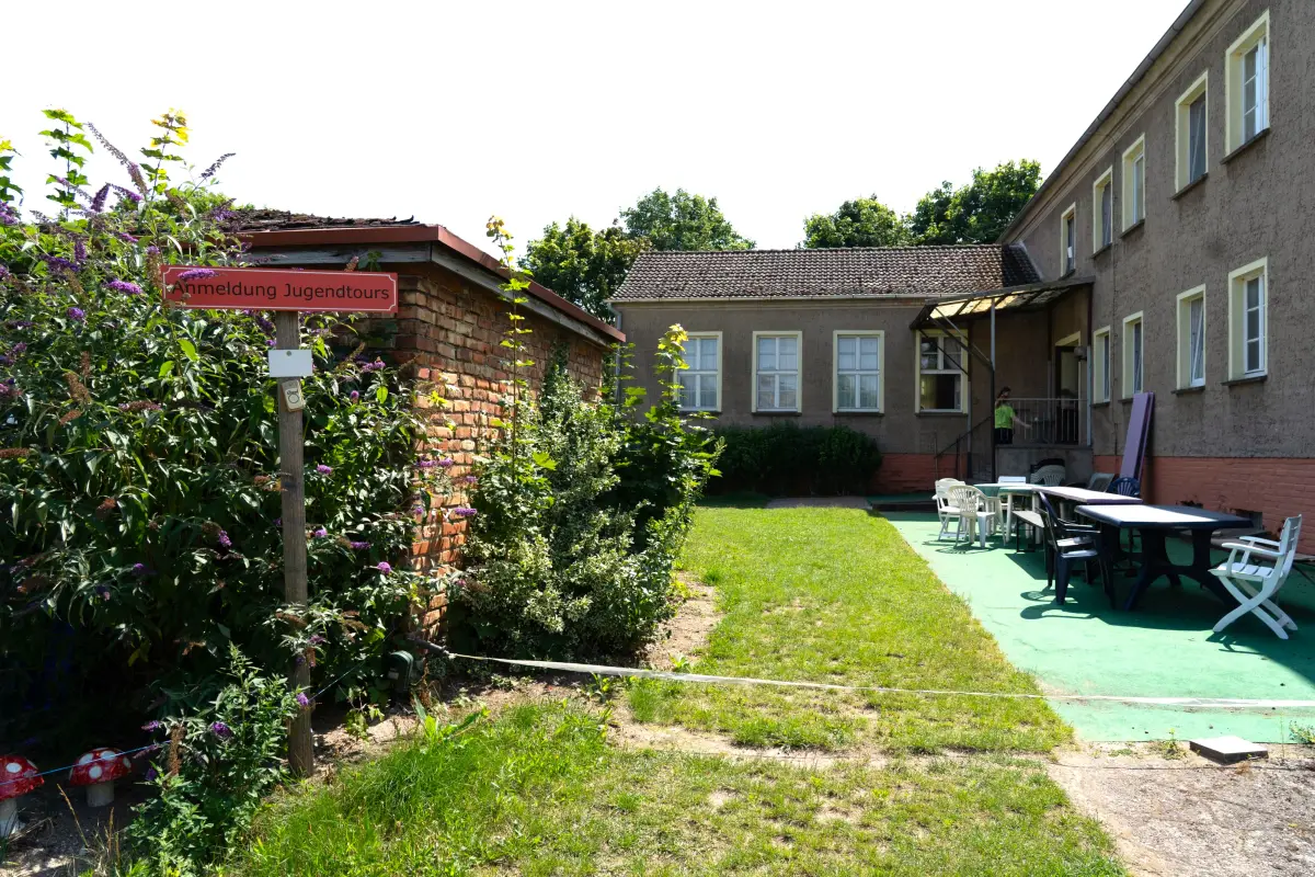 The farm courtyard with a brick outbuilding, a lawn and garden tables and chairs under the trees