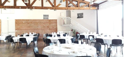 The dining hall under its wooden beams, laid for a meal