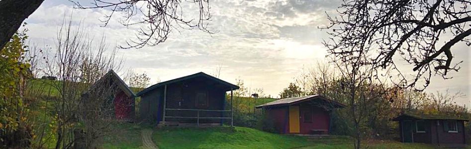 Row of wooden huts on a meadow at the Jugend-Hüttendorf Vulkaneifel