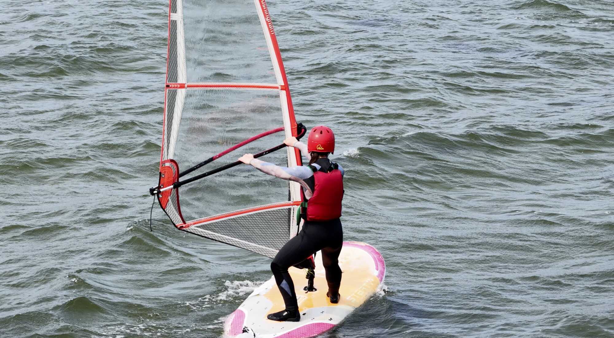 Students in wetsuits and buoyancy aids on the beach beside rigged sailing dinghies at Coláiste UISCE.
