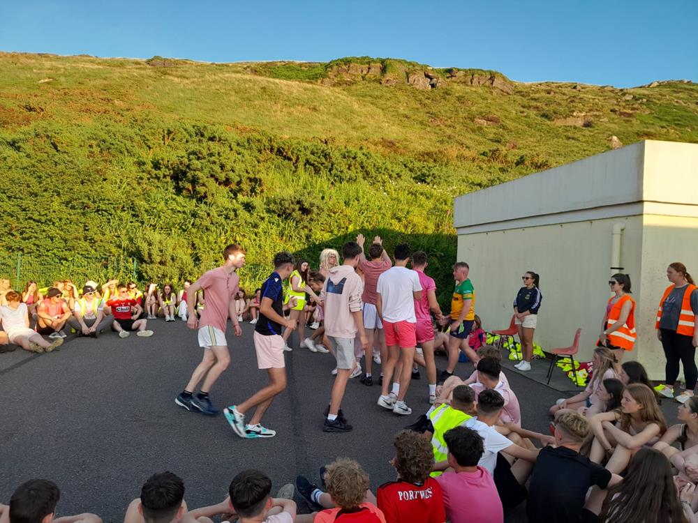Students and staff gathered outdoors beside a college building for games and dancing