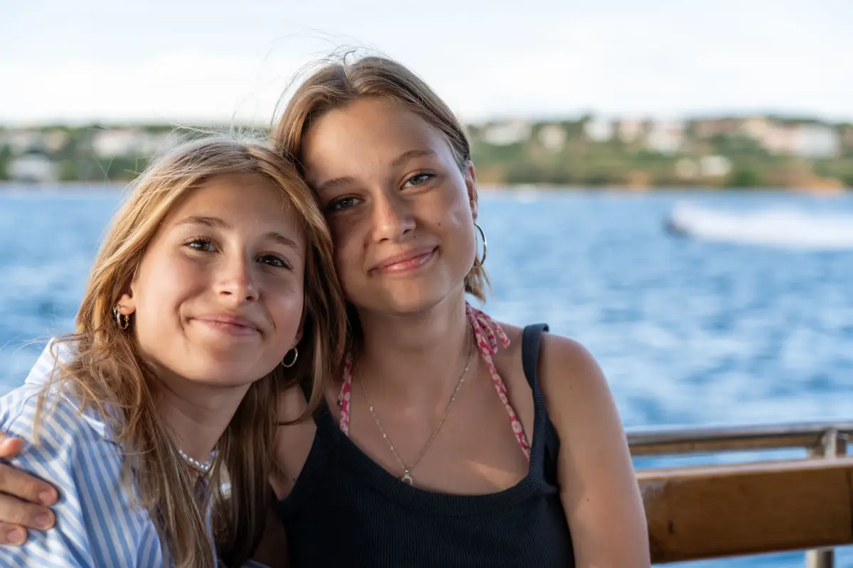 Two participants on a boat with the Adriatic and the coastline behind them