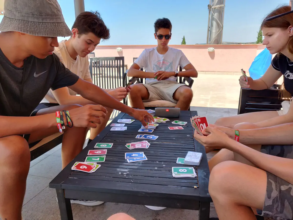 Participants playing a card game around an outdoor table on the hotel terrace